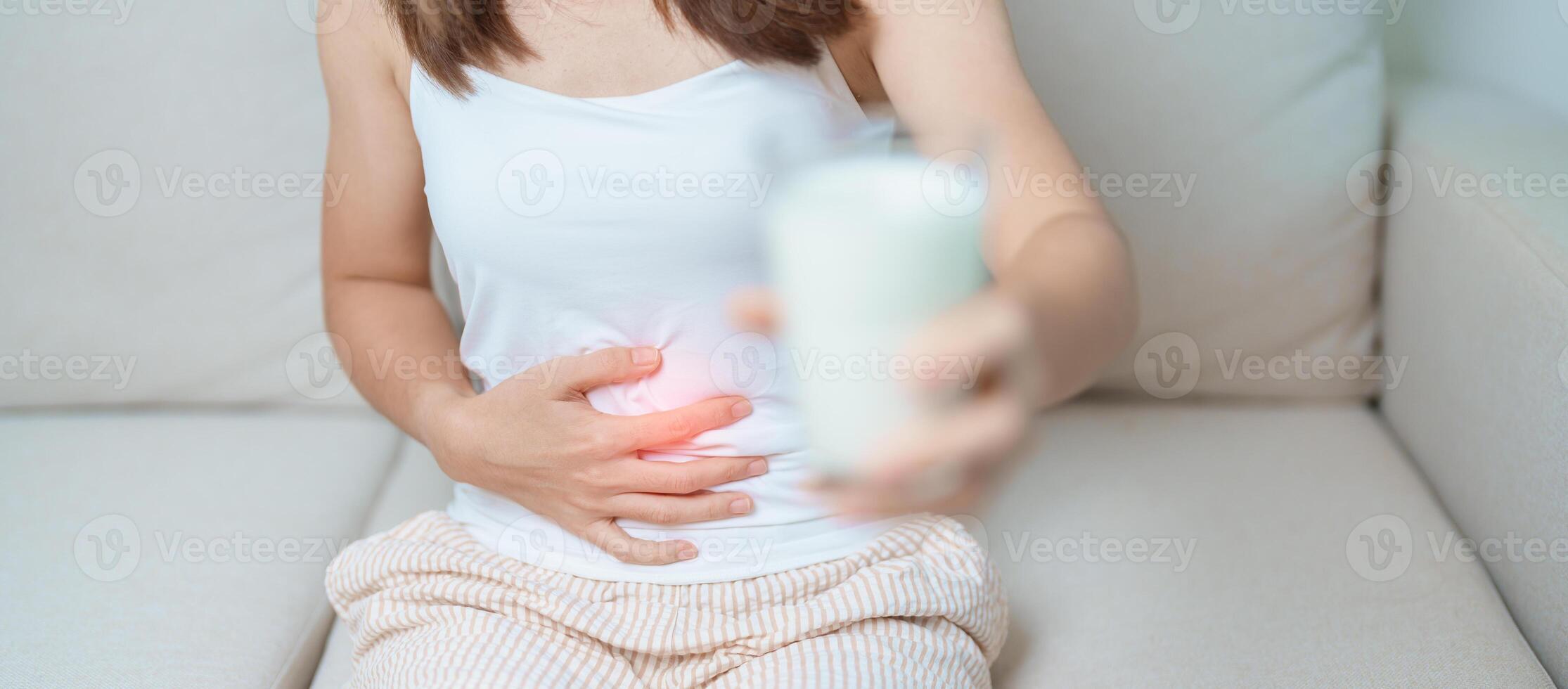 Lactose intolerance and Milk allergy concept. woman hold Milk glass and having abdominal cramps and pain when drink Cow Milk. Symptom stomach ache, Dairy intolerant, Nausea, Bloating, Gas and Diarrhea photo