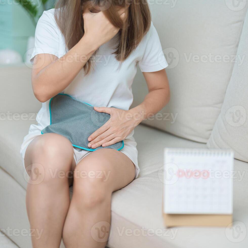 Menstruation period cycle of monthly and Stomachache concepts. woman having abdomen pain with hot water bottle and calendar, illness female suffer from premenstrual ache and body Health problem photo