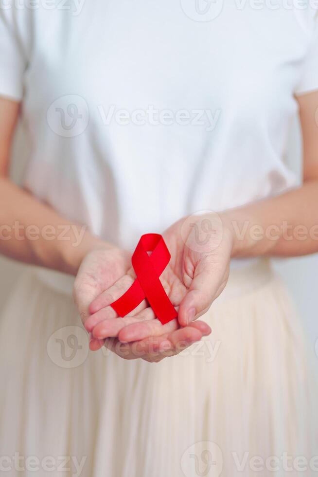 woman with Red Ribbon for December World Aids Day, acquired immune deficiency syndrome, multiple myeloma Cancer Awareness month and National Red ribbon week. Healthcare and world cancer day concept photo