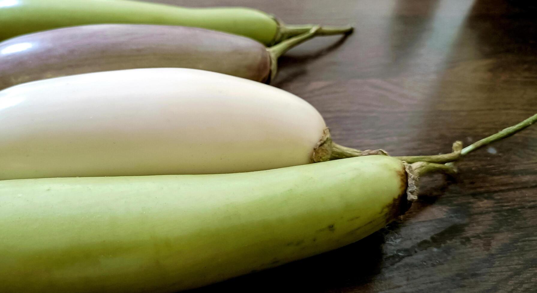 Closeup of organic white and green fresh eggplant or brinjal isolated on wooden background photo