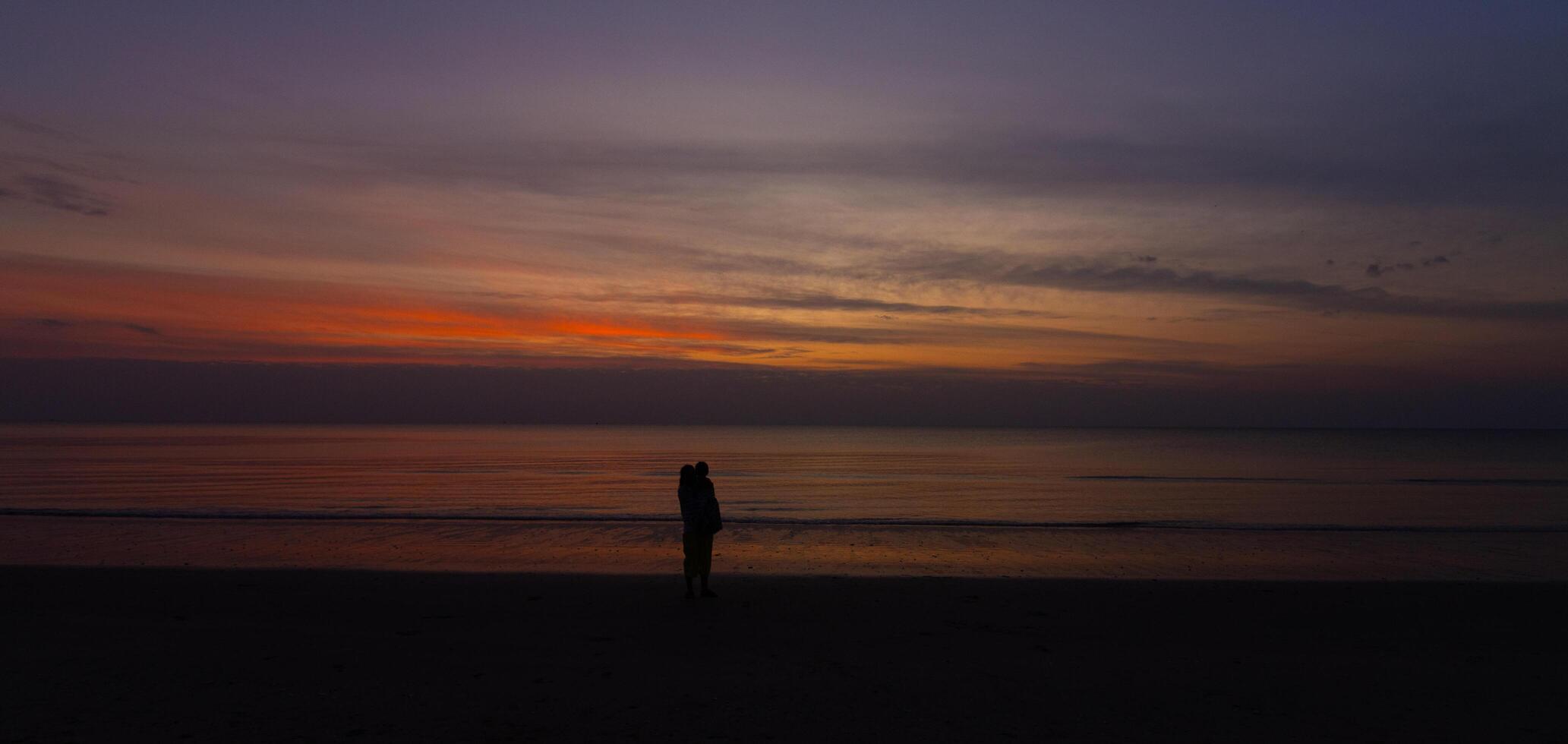 Silhouette Dark mother holding baby on the beach with Sunset Nature Coast Landscape Summer photo