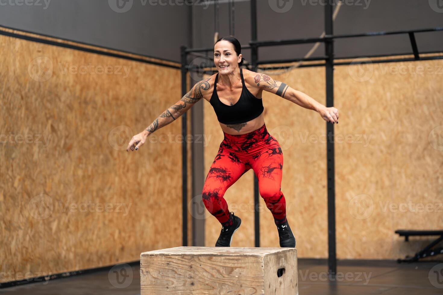 Strong woman jumping on box in a cross training gym photo