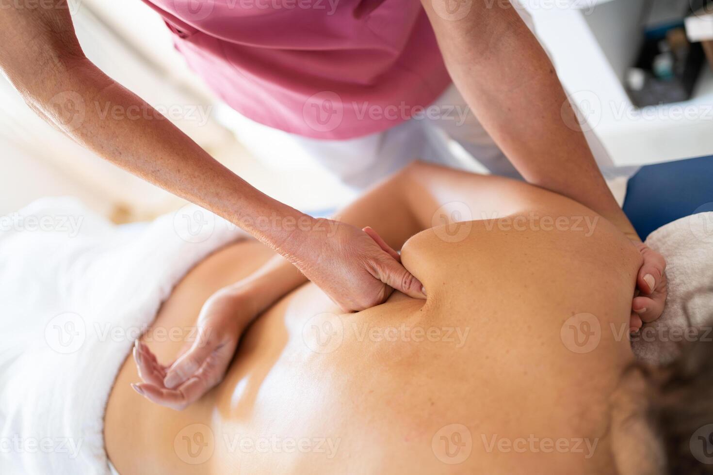 Crop female osteopathic therapist massaging back of patient photo