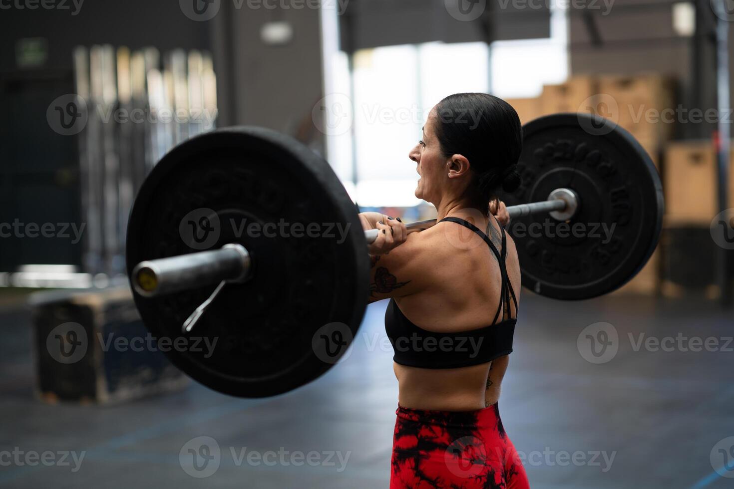 Strong mature woman lifting weights in a gym photo