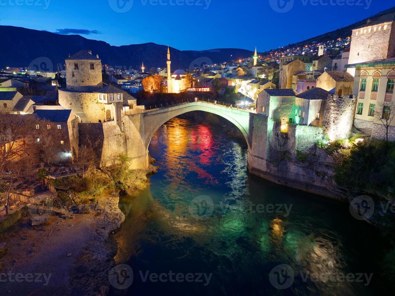 Night view of the Old Bridge in Mostar city in Bosnia and Herzegovina. Neretva river. Unesco World Heritage Site. People walking over the bridge. photo