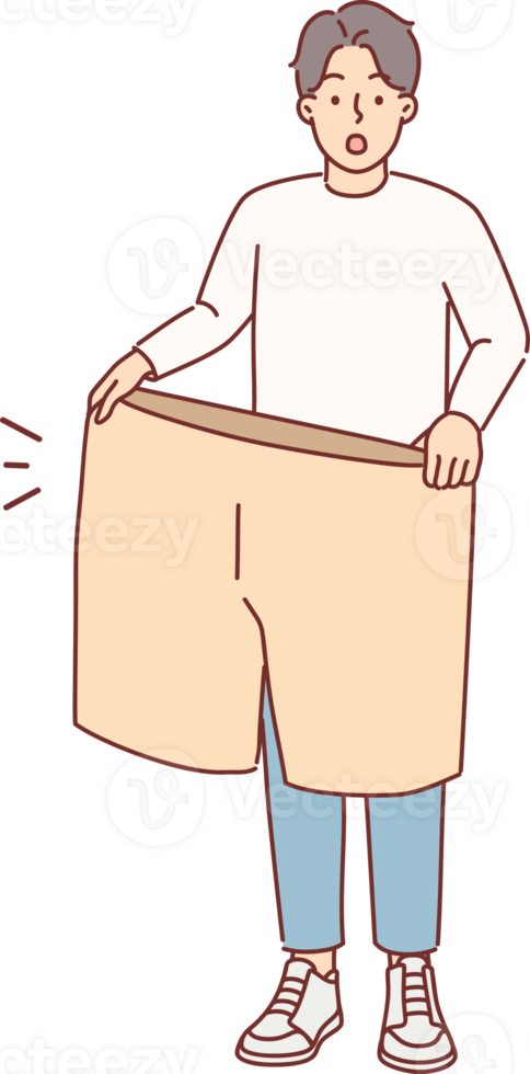 Lost weight man with big shorts in hands is surprised at size of own clothes from past. Lost weight guy boasts about excellent results of diet and regular exercise that help achieve goal png