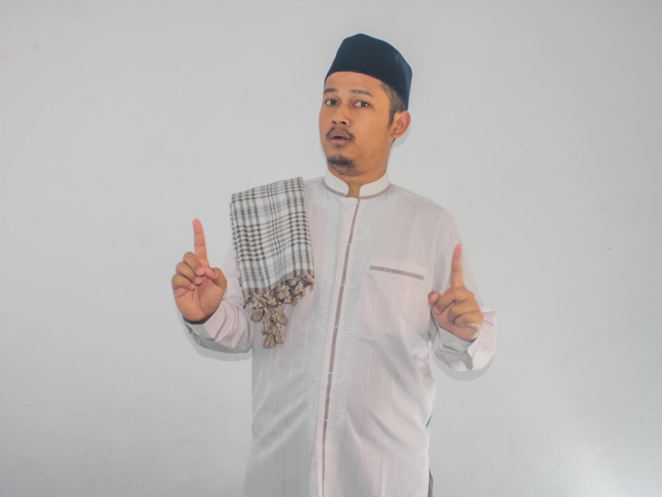Moslem Asian man shocked at the camera with both hands pointing up photo