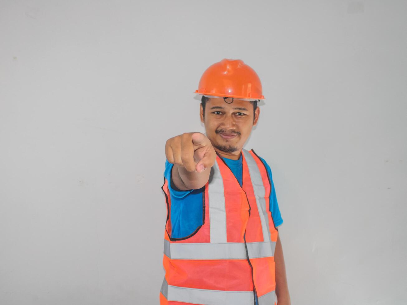 A man wearing construction pointing forward gesture choosing someone against white background photo