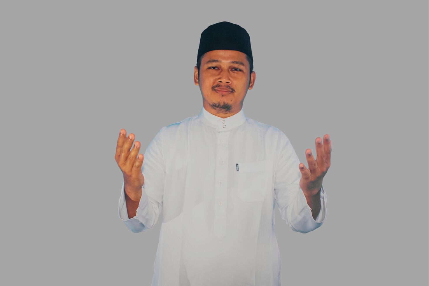 Moslem Asian man seriously prayer at the camera with arms open doing prayer gesture photo
