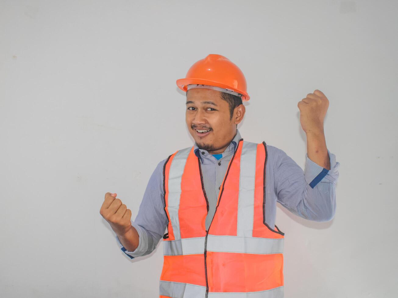 Asian man worker wearing safety helmet lookis happy celebrating his victory by clenching his fists against photo