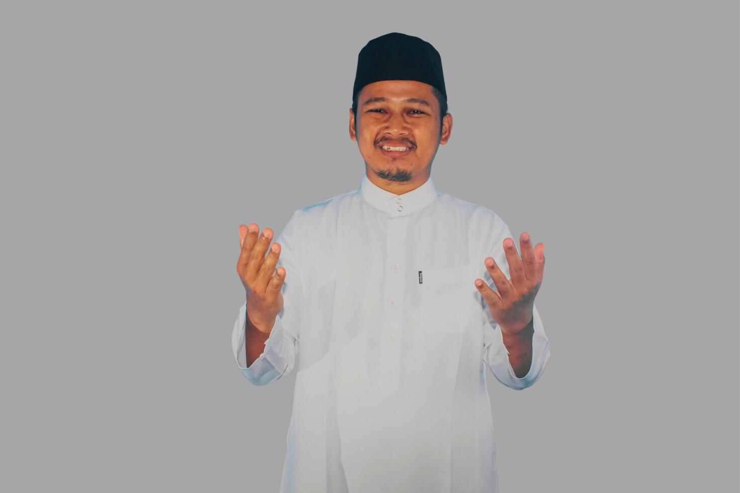 Moslem Asian man smiling at the camera with arms open doing prayer gesture photo