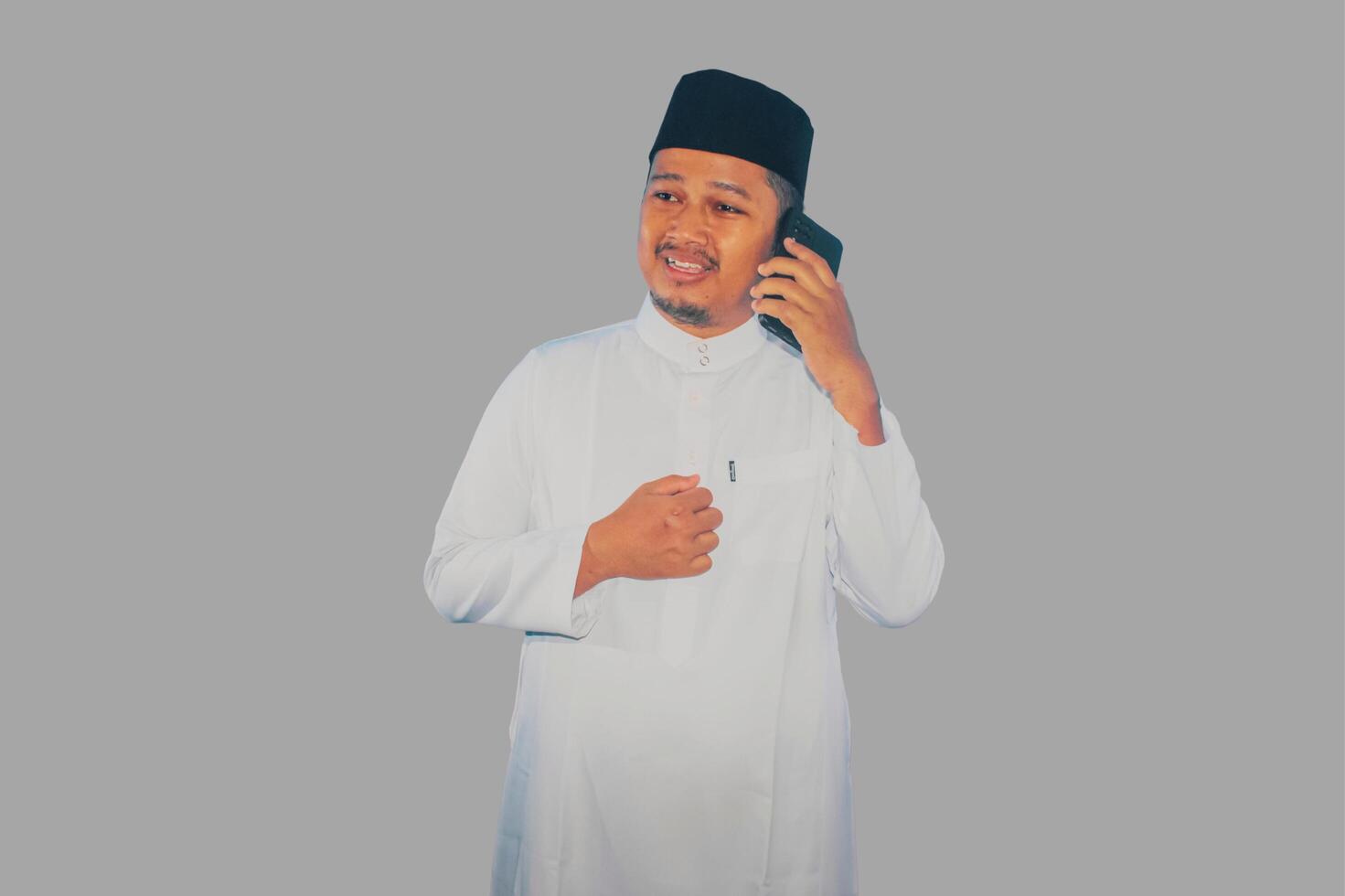 Moslem Asian man clenched fist showing excitement when looking to his mobile phone photo