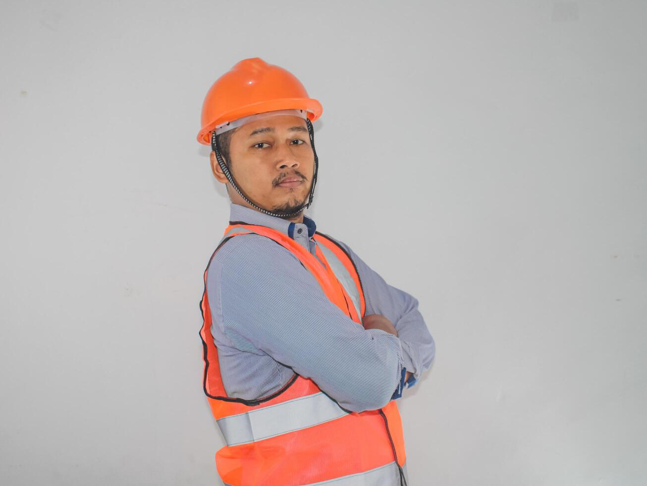 Asian constructor worker man with safety vest stand croosed his arm with confidence gesture photo