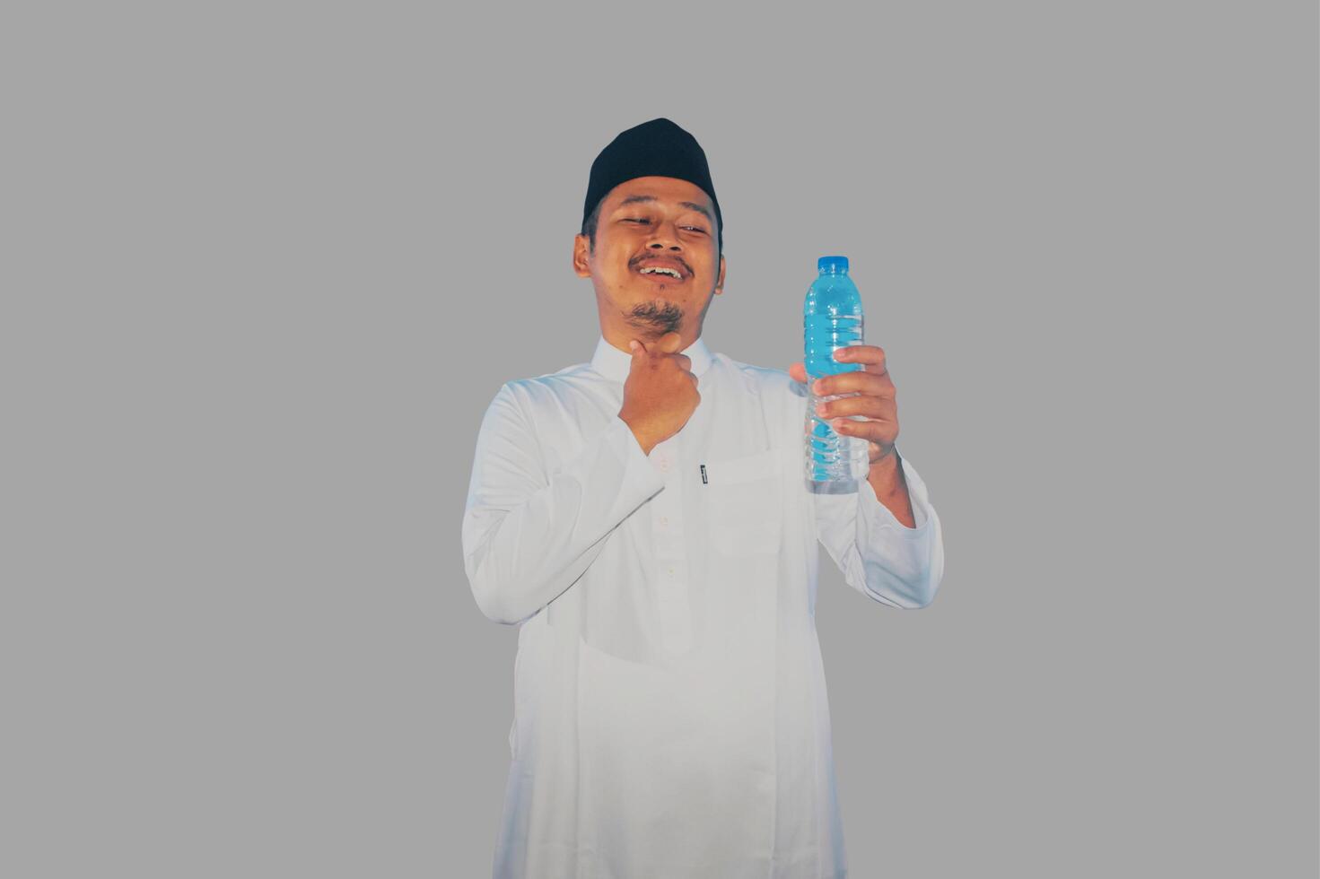 Moslem man holding a drink and touching his throat showing relieved expression photo