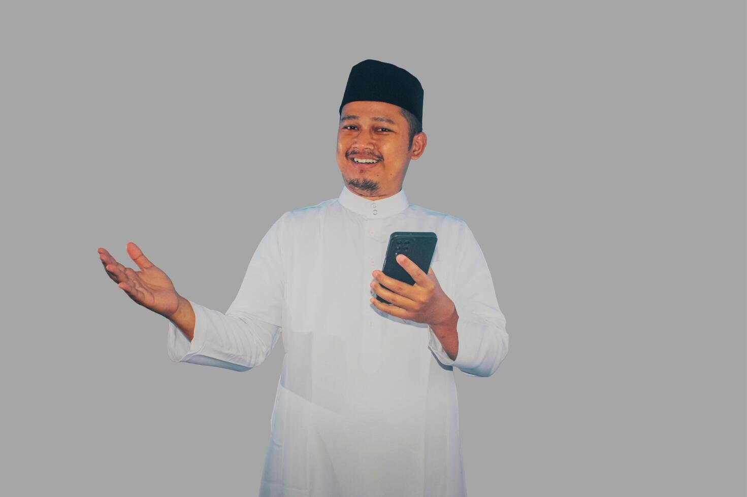 Moslem Asian man smiling happy when holding a mobile phone photo