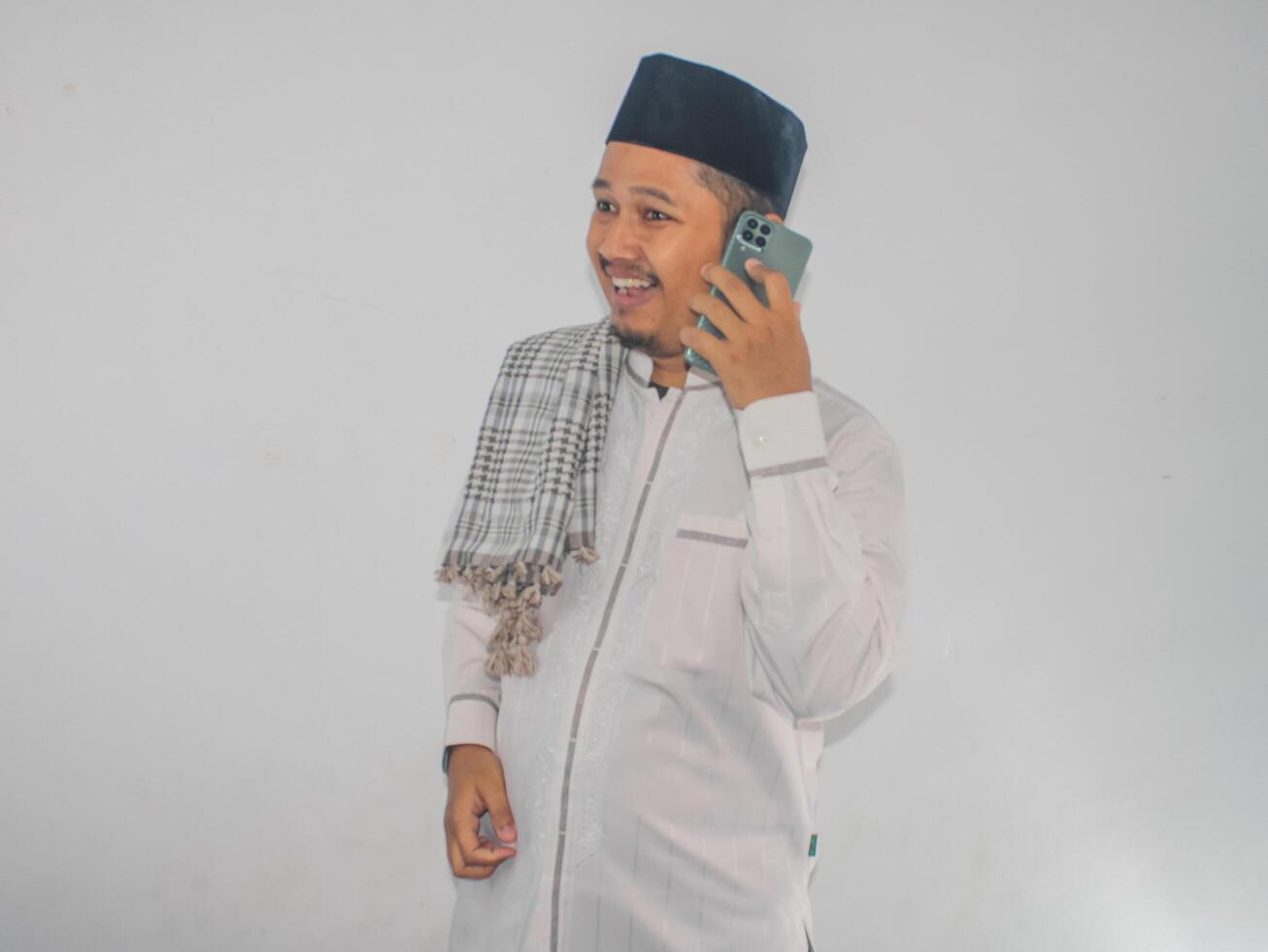 Moslem Asian man smiling happy while calling his family during Ramadan celebration photo