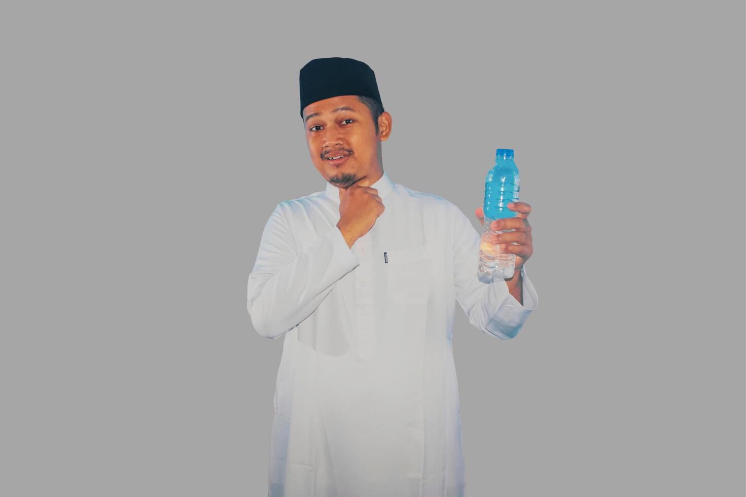 Moslem man holding a drink and touching his throat showing relieved expression photo