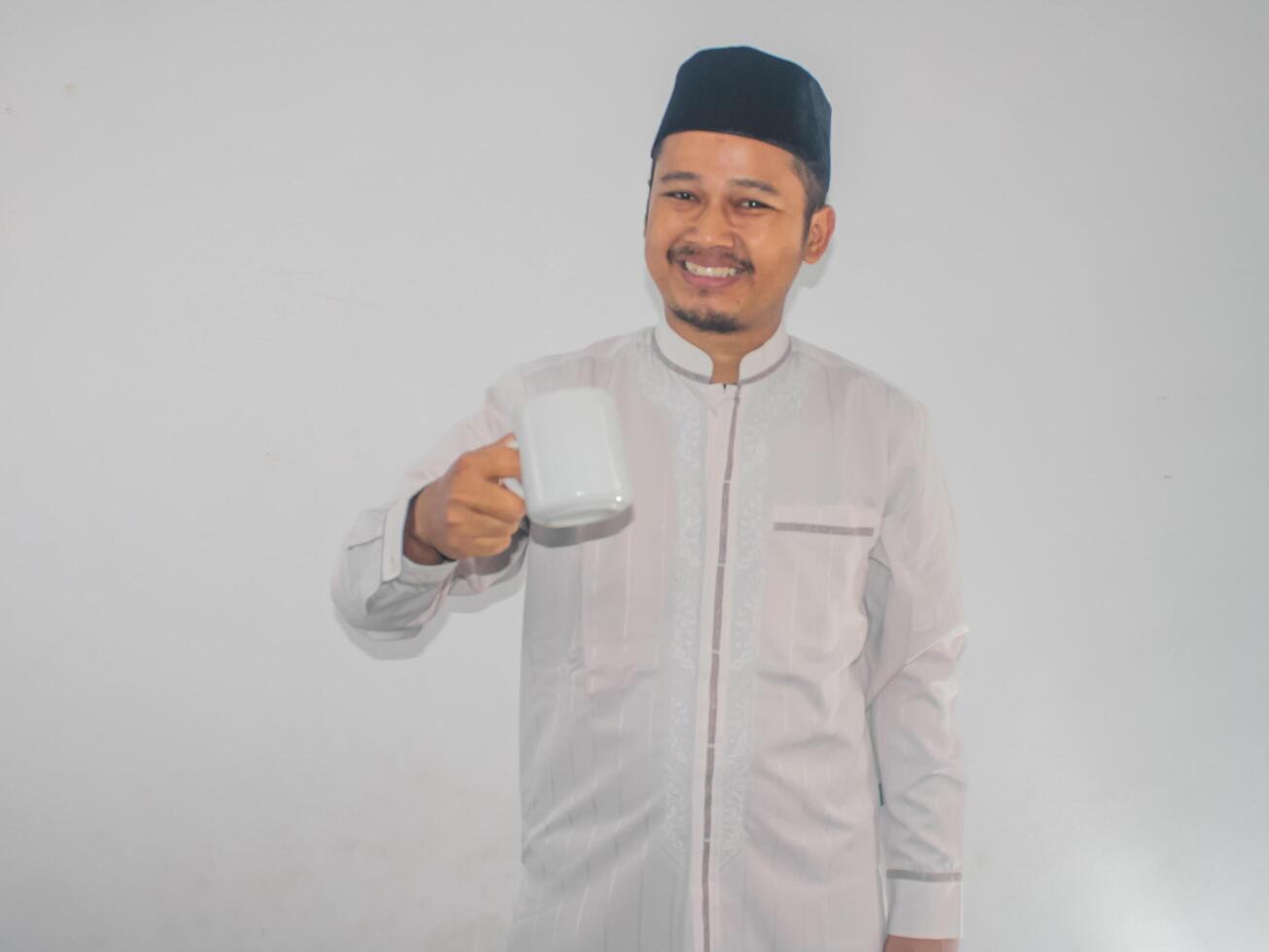 Moslem Asian man smiling at the camera while holding a drinking glass photo