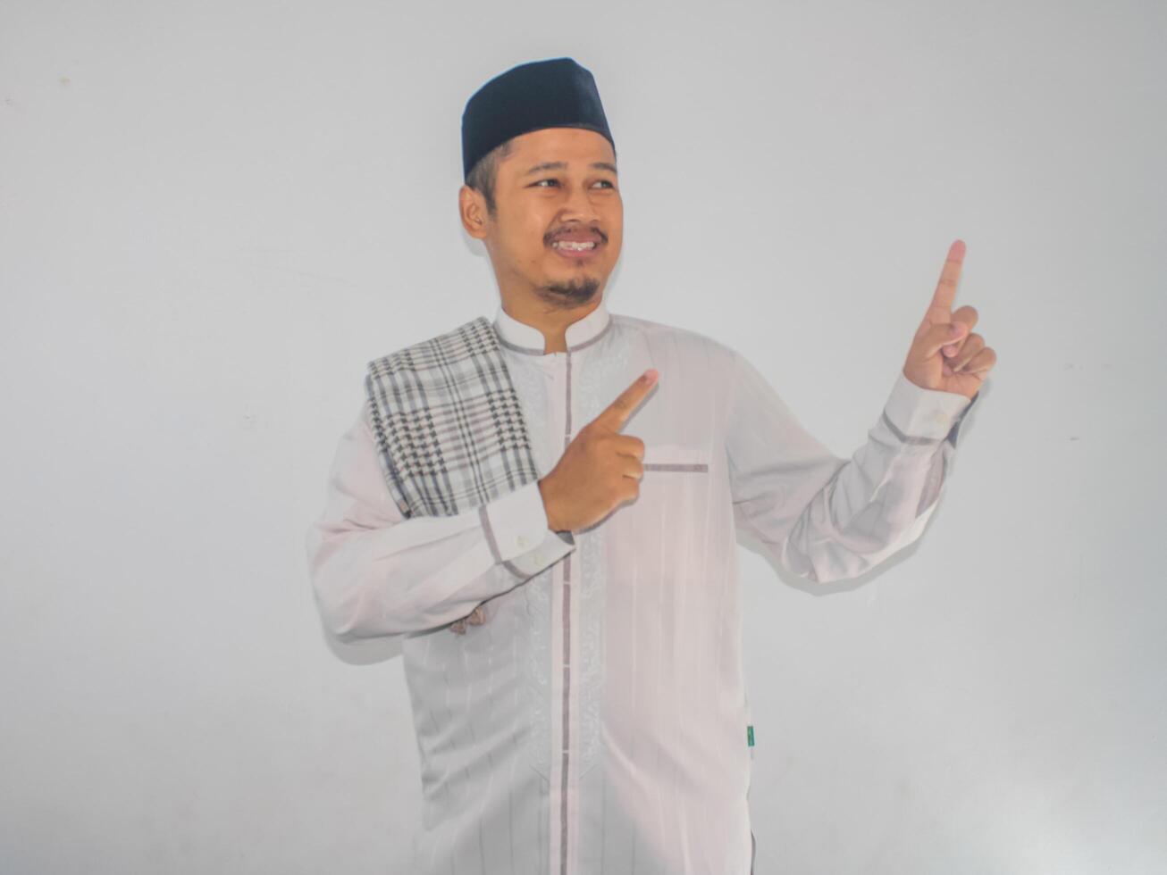 Moslem Asian man smiling and pointing both hands to the right side photo