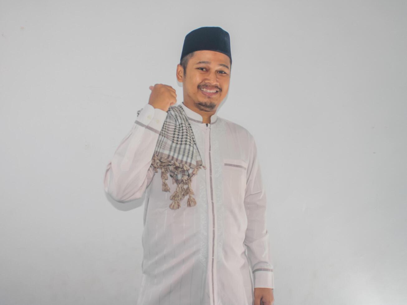 Moslem Asian man smiling at the camera and pointing to the left side photo