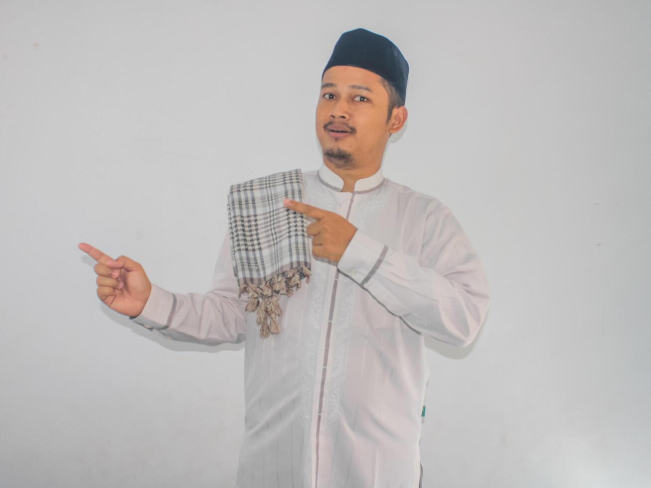 Moslem Asian man smiling and pointing both hands to the right side photo