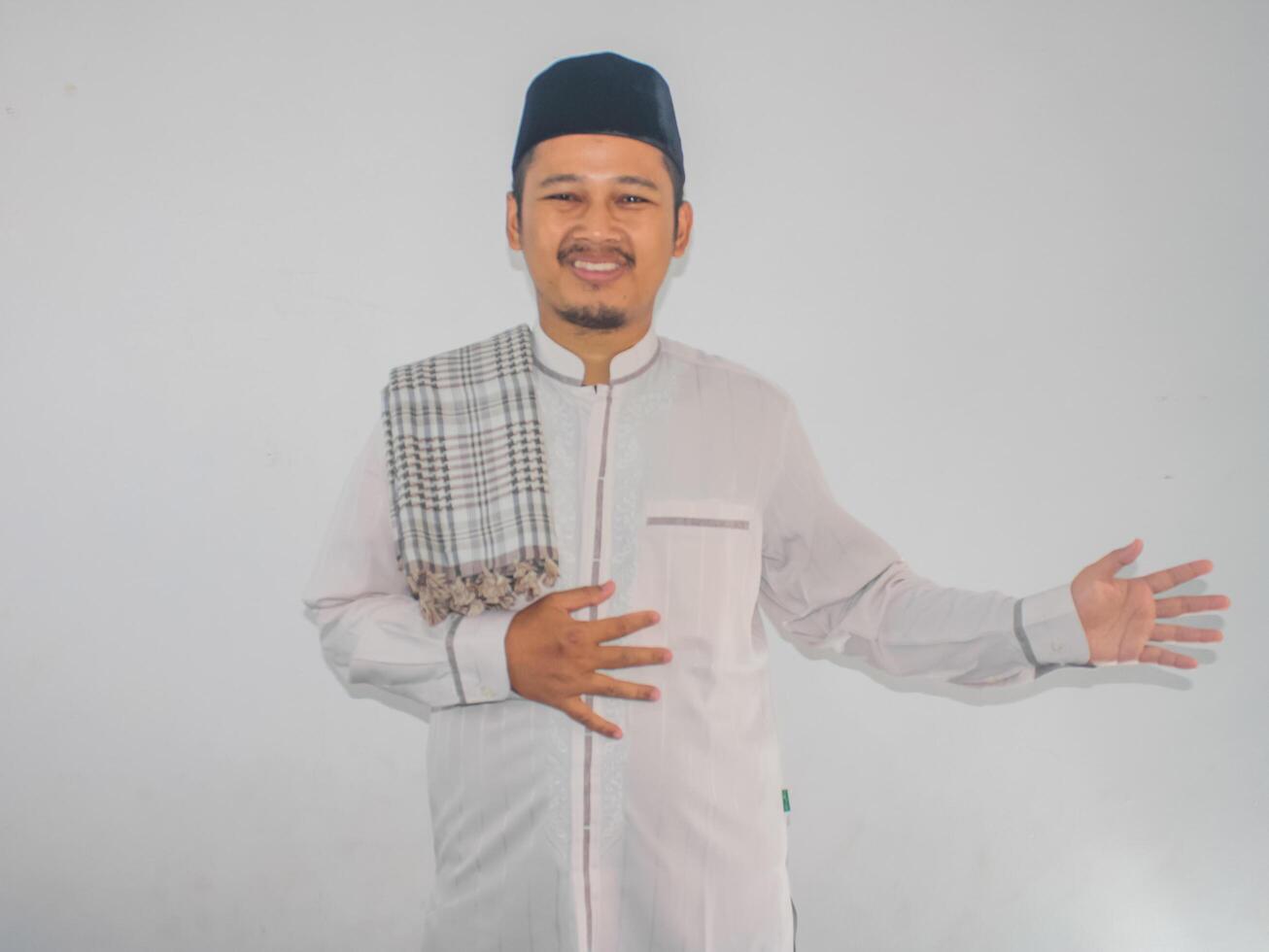 Moslem Asian man smiling at the camera while letting someone to coming inside photo