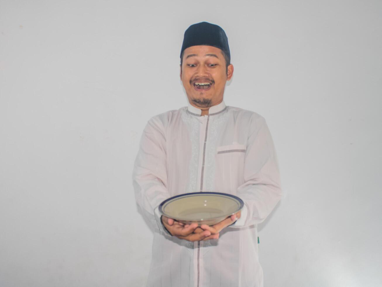 musulmán asiático hombre sonriente contento mientras participación vacío cena plato foto