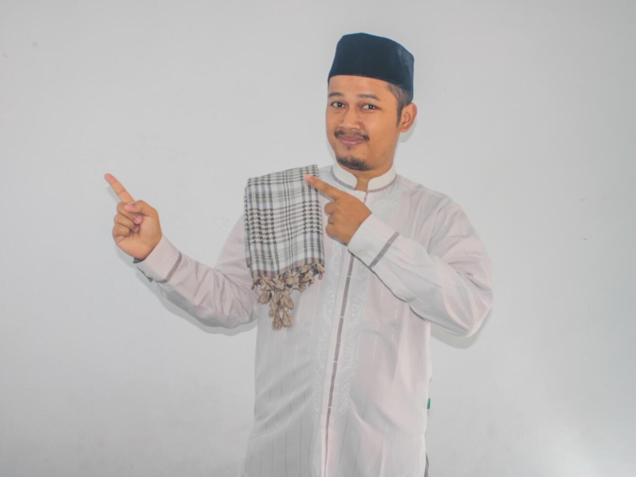 Moslem Asian man smiling and pointing both hands to the right side photo