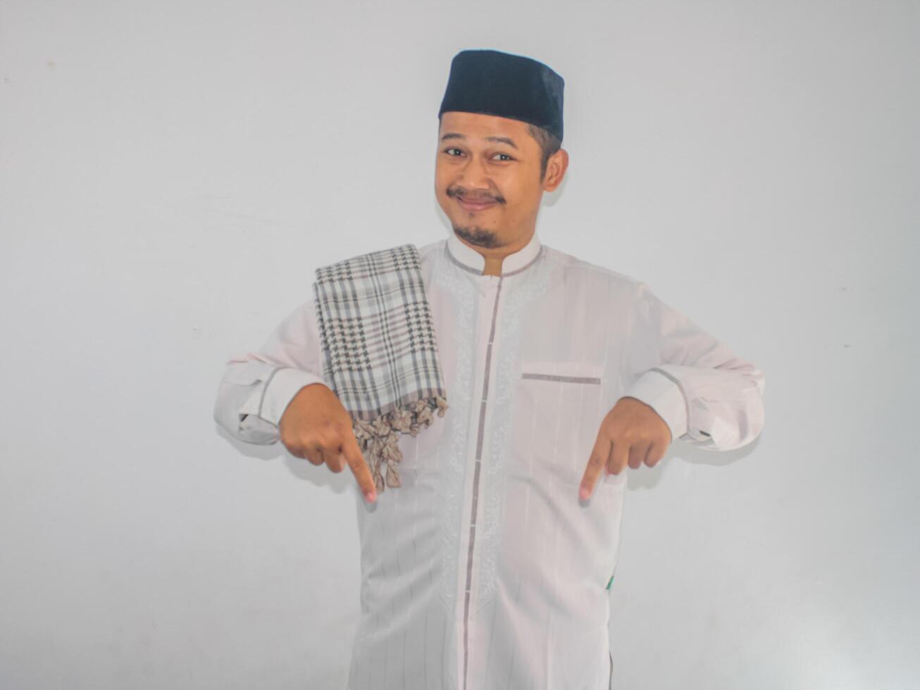 Moslem Asian man smiling at the camera with both hands pointing down photo