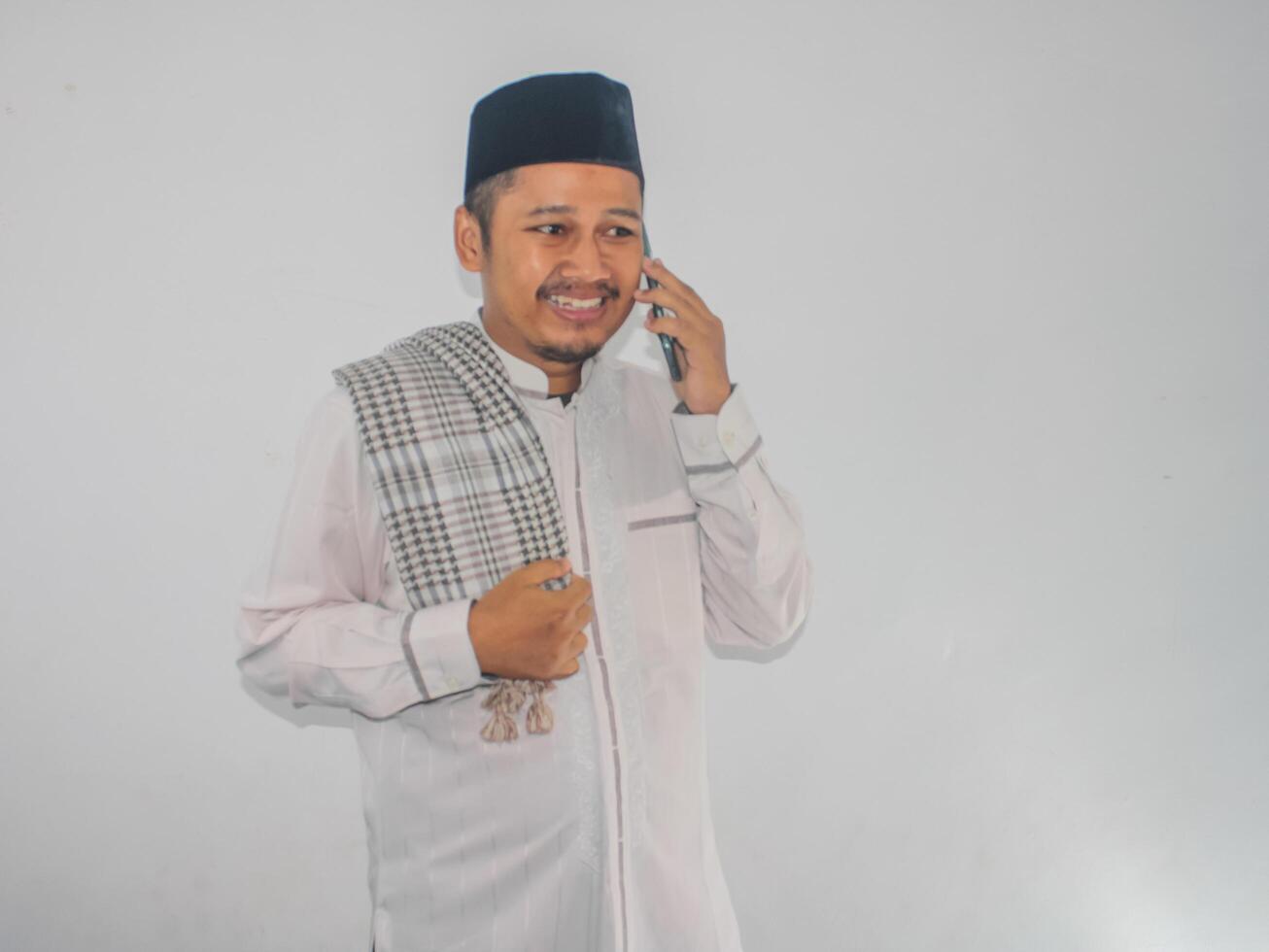 Moslem Asian man smiling happy while answering a phone call photo