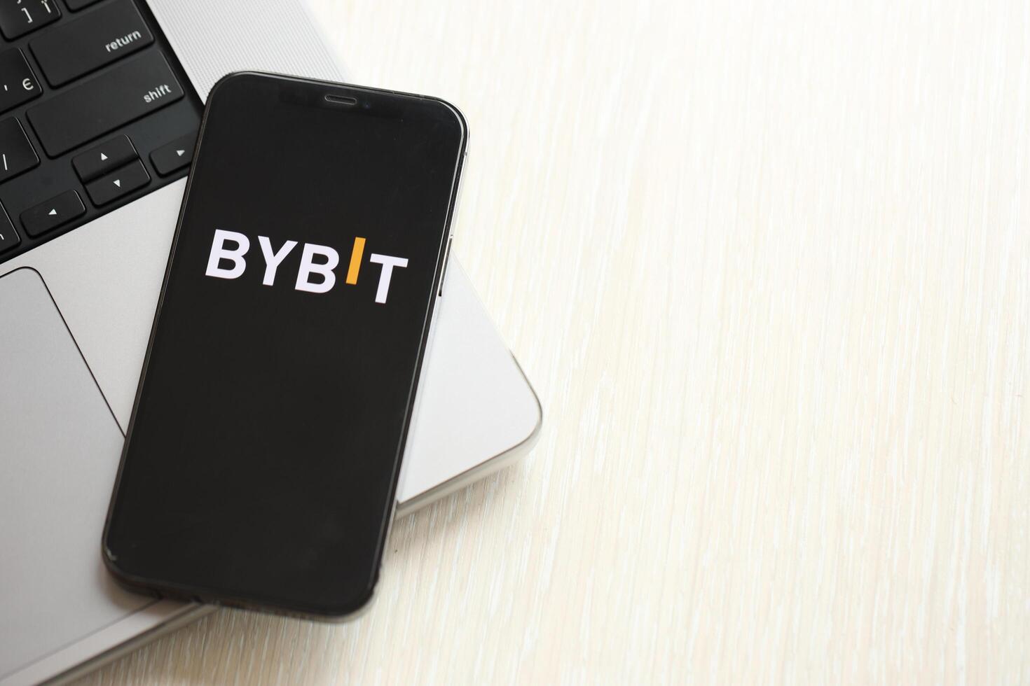 KYIV, UKRAINE - MARCH 15, 2024 Bybit logo on iPhone display screen on MacBook panel logo on iPhone display screen with dollars and bitcoins on MacBook photo