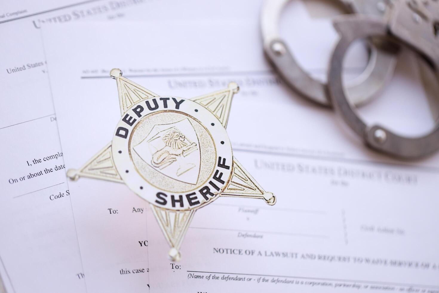 KYIV, UKRAINE - MARCH 9, 2024 US Deputy Sheriff badge with handcuffs on many US District Court warrants and complaints photo