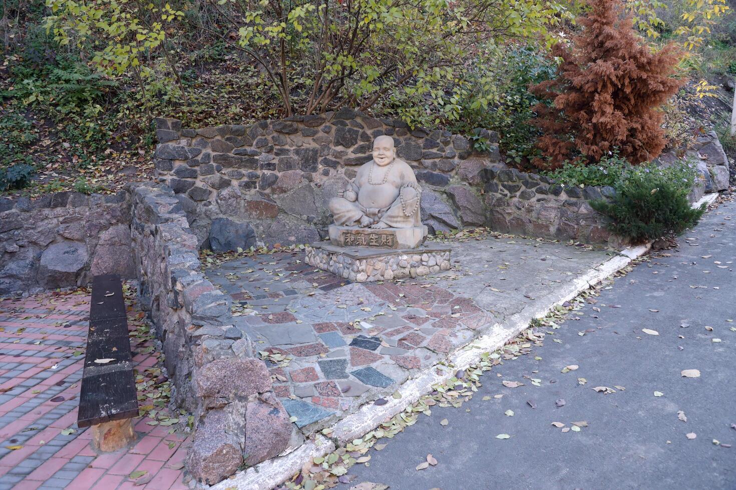 Cherkasy, UKRAINE - OCTOBER 20, 2021 Joyful Buddah concrete grey statue close to White Lotus buddhist temple photo