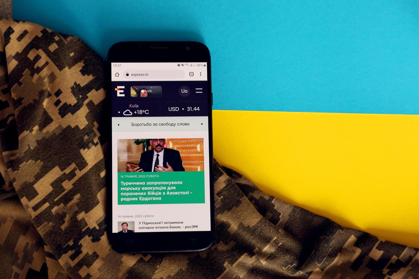 KYIV, UKRAINE - 4 MAY, 2023 Espreso TV ukrainian news portal on smartphone screen with ukrainian flag and camouflage fabric photo