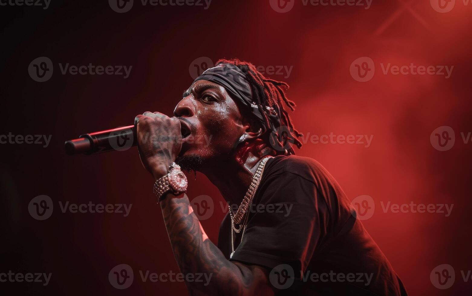 A African American singer of performer singing on stage, illuminated by dramatic red lighting amidst smoke. photo