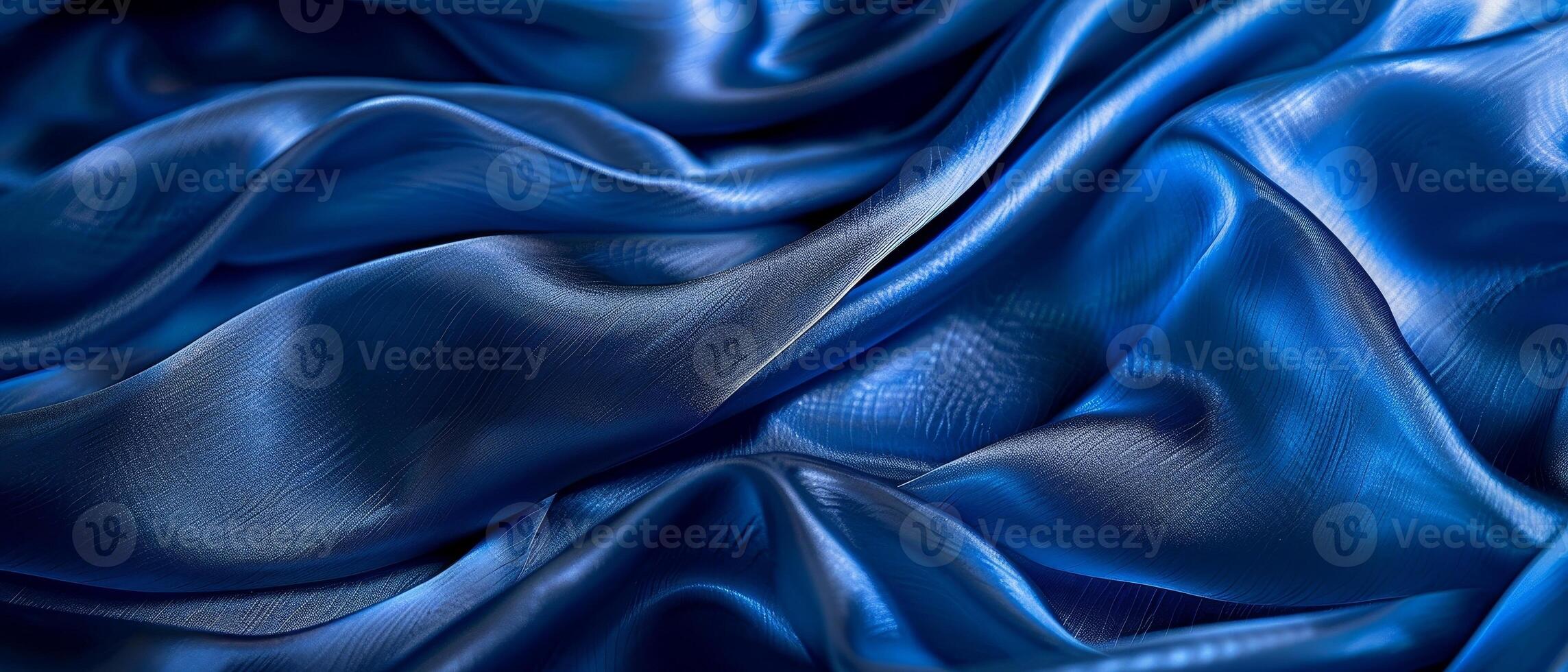 Rippling azure blue satin draped in fluid waves, the light playing across the lustrous folds of the vibrant fabric. photo