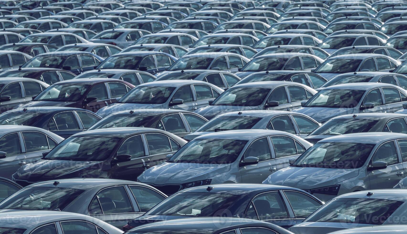 filas de un nuevo carros estacionado en un distribución centrar en un coche fábrica en un soleado día. parte superior ver a el estacionamiento. foto