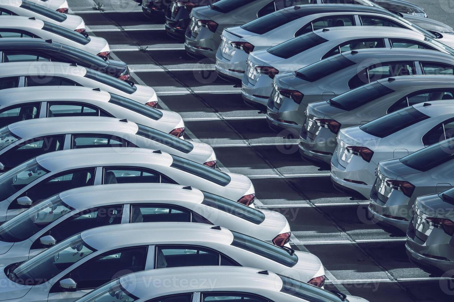 Rows of a new cars parked in a distribution center on a car factory on a sunny day. Top view to the parking. photo