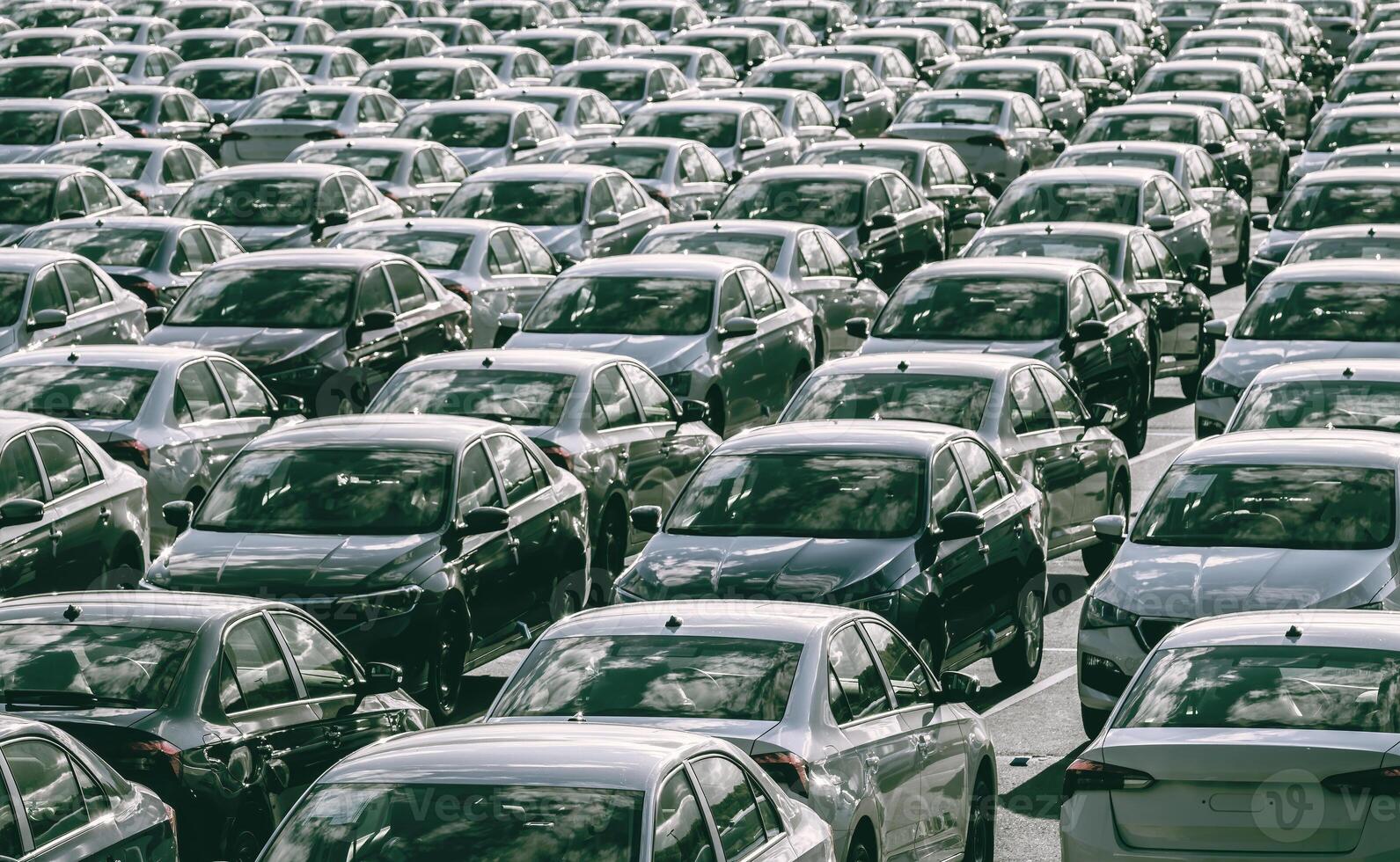 filas de un nuevo carros estacionado en un distribución centrar en un coche fábrica en un soleado día. parte superior ver a el estacionamiento. foto