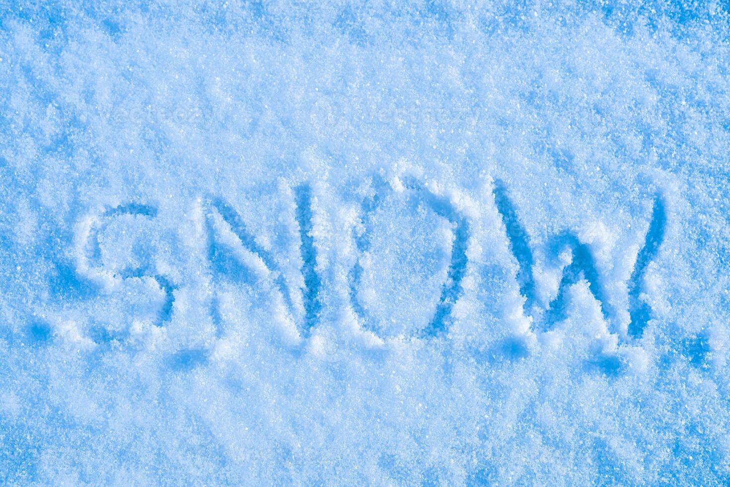 The word snow written on the snow. Winter and cold weather concept. photo