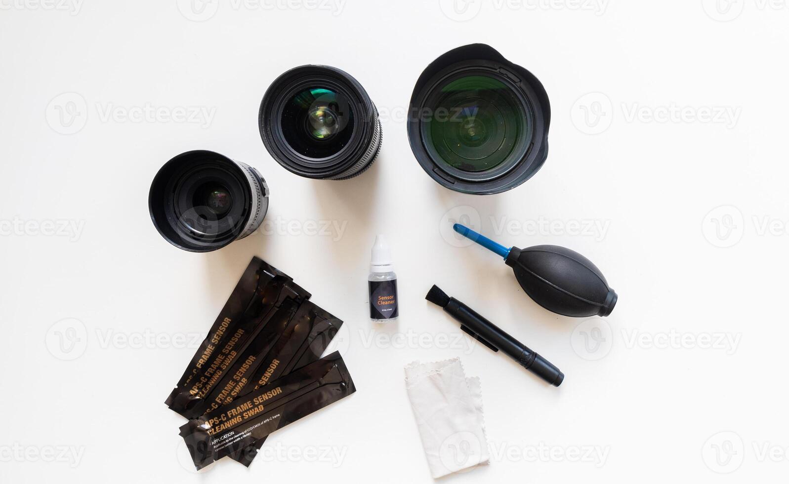 Dslr lenses, filters, swabs, sensor cleaner, air blower, microfiber and lens pen knolled on a textured yellow background.Cleaning set for photographic equipment maintenance photo
