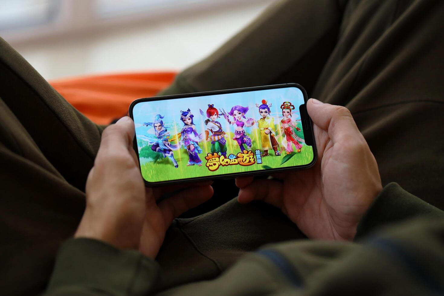 Fantasy Westward Journey mobile iOS game on iPhone 15 smartphone screen in male hands during mobile gameplay photo