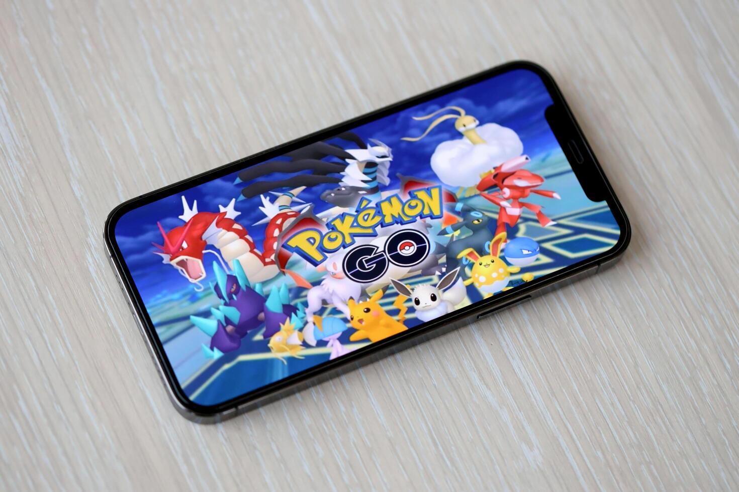Pokemon GO mobile iOS game on iPhone 15 smartphone screen on wooden table during mobile gameplay photo
