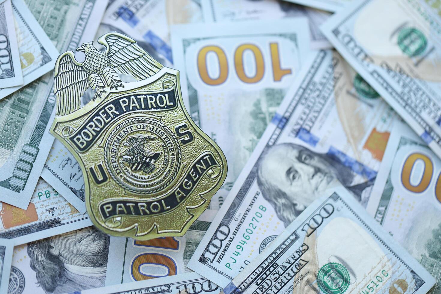 KYIV, UKRAINE - MARCH 9, 2024 US Border Patrol Agent badge on many US hundred dollar bills photo