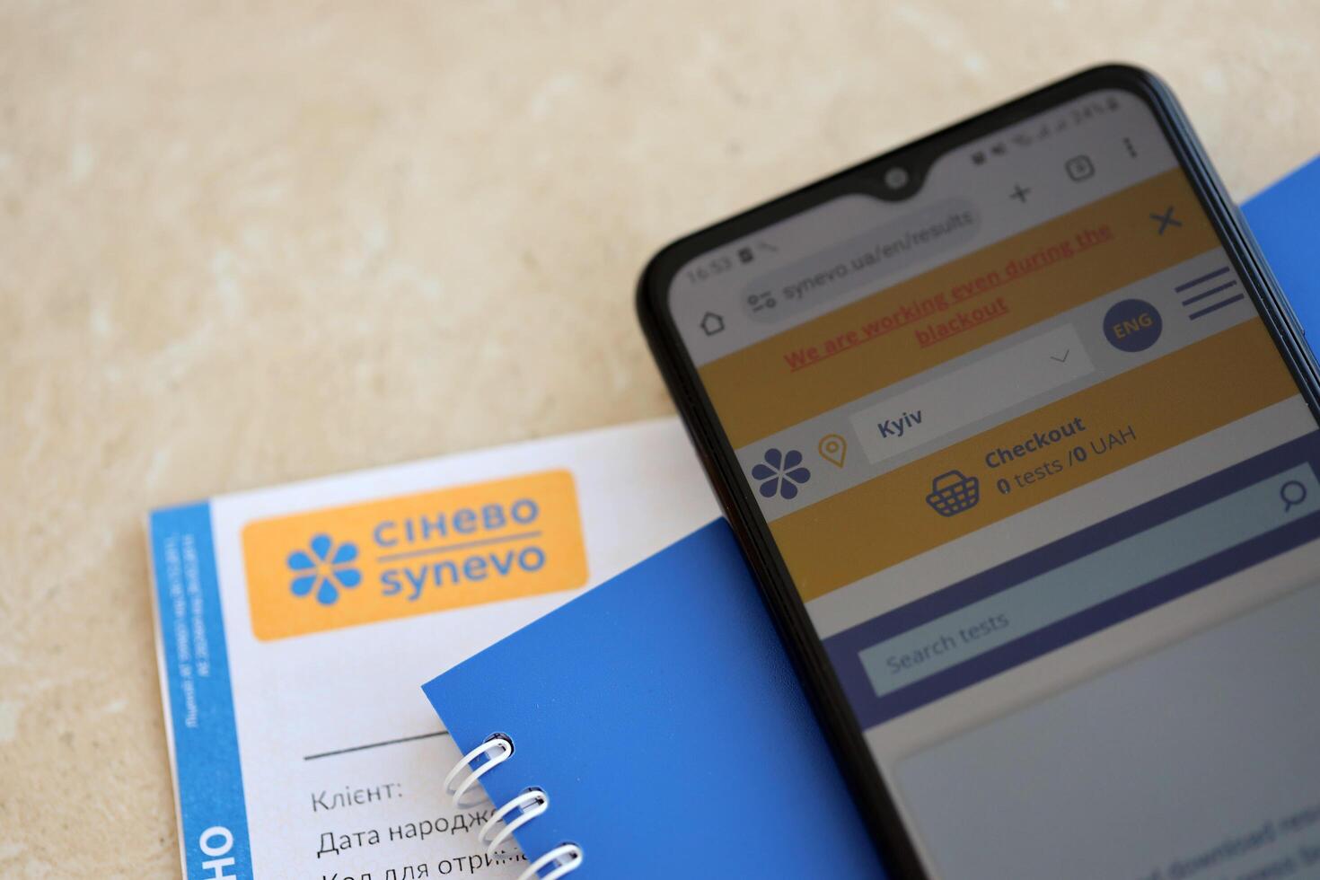 KYIV, UKRAINE - 4 MAY, 2023 Synevo medical analysis results and smartphone with synevo official website on screen photo