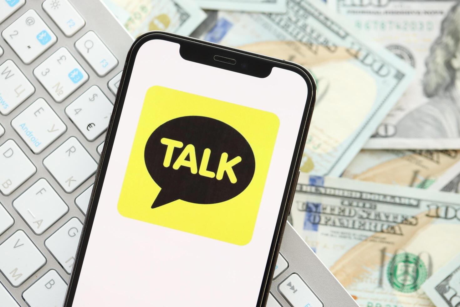 KYIV, UKRAINE - APRIL 1, 2024 KakaoTalk messenger icon on smartphone screen on many usd money bills photo