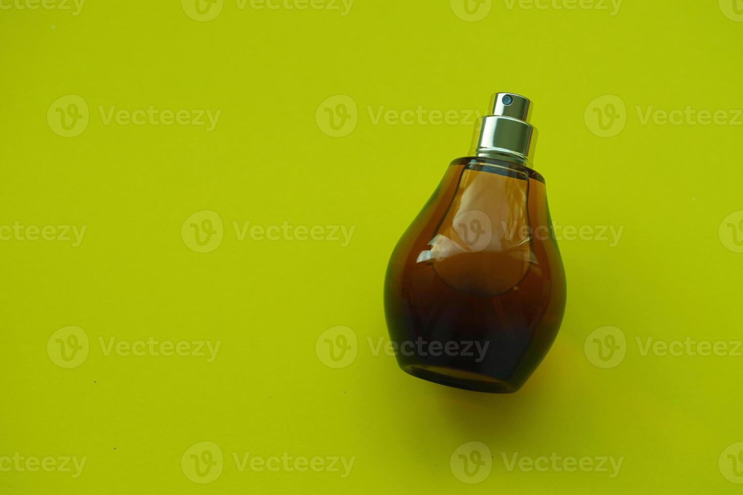 Women fragrance perfume bottle on yellow background close up. Unnamed blank sprayer bottle of perfume photo