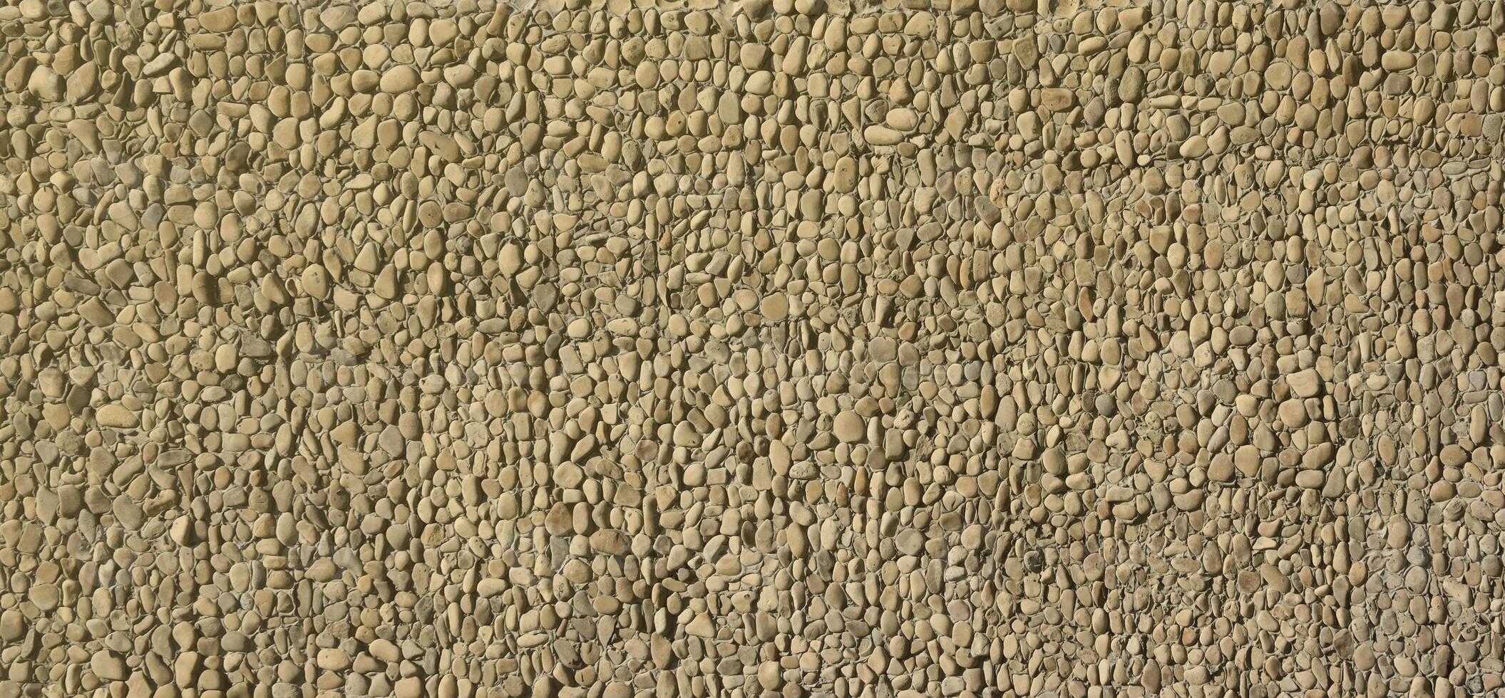 Texture of a stone wall with small round pebble stones. Part of a stone wall as a background or texture photo
