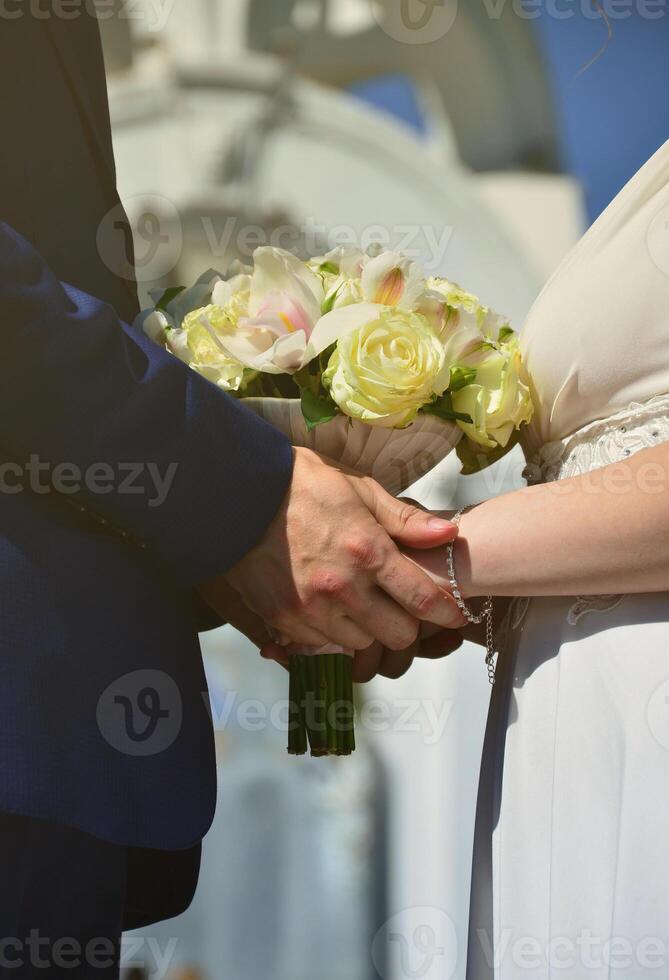 The newlywed couple is holding a beautiful wedding bouquet. Classical wedding photography, symbolizing unity, love and the creation of a new family photo