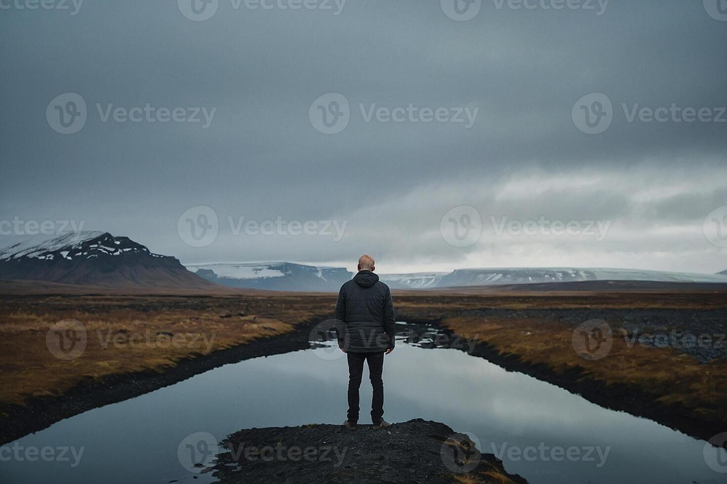 man standing on the edge of the cliff looking at the ocean photo